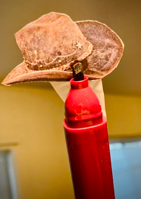 A hat on top of a red gas cylinder

Description automatically generated